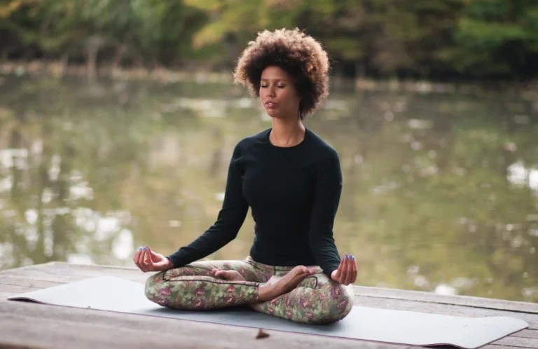 Woman meditating in lotus pose near tranquil lake