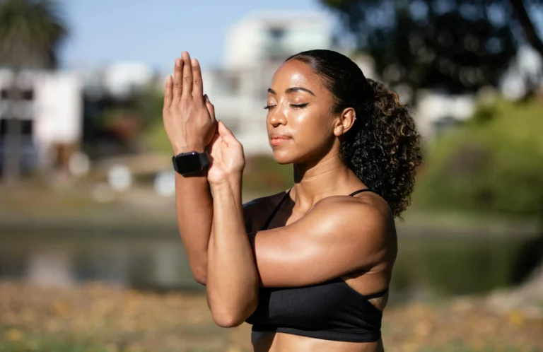 Young woman practicing mindful yoga and wellness rituals by a calm lake with autumn trees.